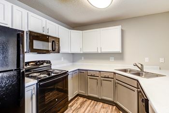 an empty kitchen with white cabinets and black appliances